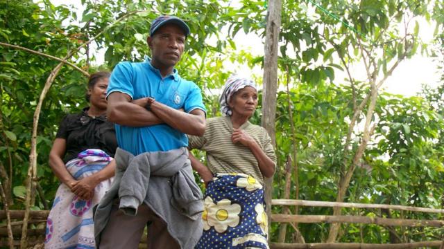 Imagem mostra o produtor de baunilha Leon Charles e duas mulheres de sua família, na plantação, em Madagascar. Homem teve a colheita roubada e diz ter perdido tudo.