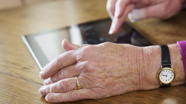 Mão envelhecida tocandocasas de apostas para menor de 18 anosiPad sobre a mesa