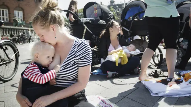 Madre amamantando a su bebé en una plaza.