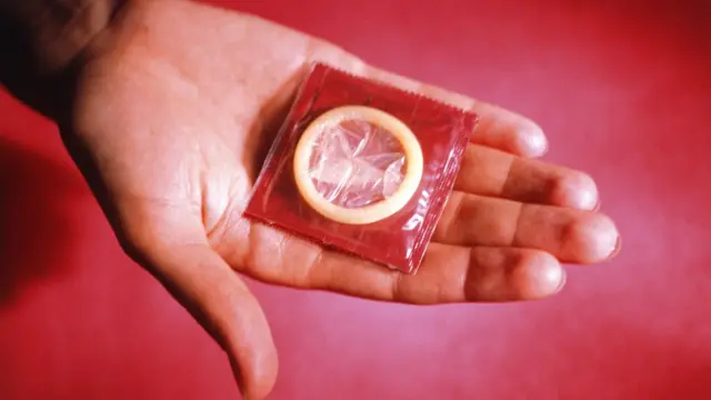 Mano mostrando preservativo.