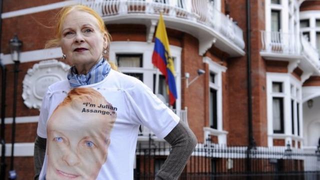Vivienne Westwood com camisa estampando rosto de Assange, em frente a edifício
