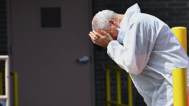 A medical personnel rubs his face outside the Wyckoff Heights Medical Center on April 07, 2020