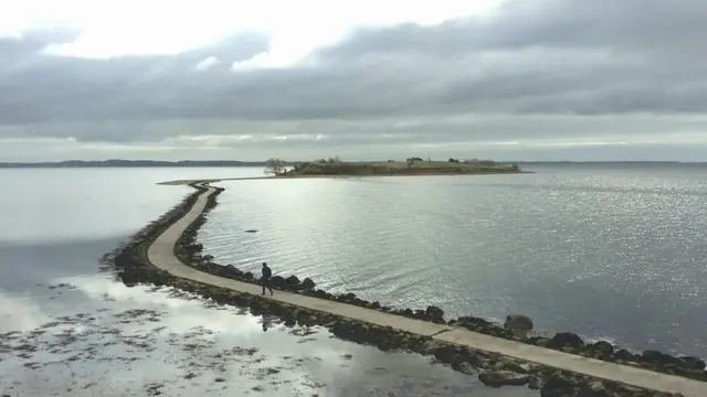 Una persona caminando por un sendero rodeado de agua
