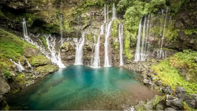 Ukiran jalur sungai di atas batu vulkanik yang menciptakan pemandangan dan air terjun yang indah.