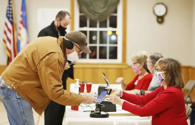 Gary Kuntz (L) of Edinburg, Ohio, the first voter in line at the Edinburg Town Hall polling location receives his ballot from Poll worker Debbie Stanatis (R) at a polling location at the Edinburg Town Hall in Edinburg, Ohio, USA, 03 November 2020.