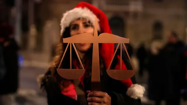 متظاهرة ترفع ميزان العدالة.