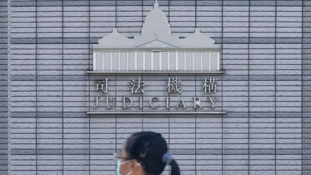一位女孩走过香港西九龙法院大楼的香港司法机构标志(13/7/2020)