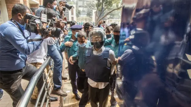 অভিজিৎ রায় হত্যা মামলার একজন অভিযুক্তকে পুলিশ হেলমেট পড়িয়ে আদালতে নিয়ে যাচ্ছে, ১৬/০২/২০২১