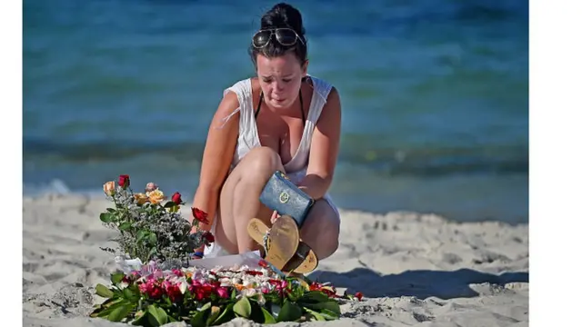 Жінка покладає квіти на місці загибелі туристів на пляжі Мархаба, Туніс