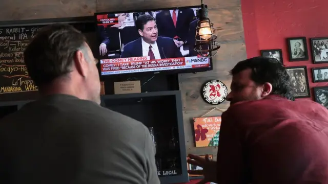 Gente mirando a Comey declarar.