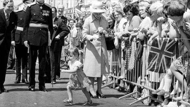 Двухлетняя Трэйси Сэлби убегает, подарив королеве букетик роз.