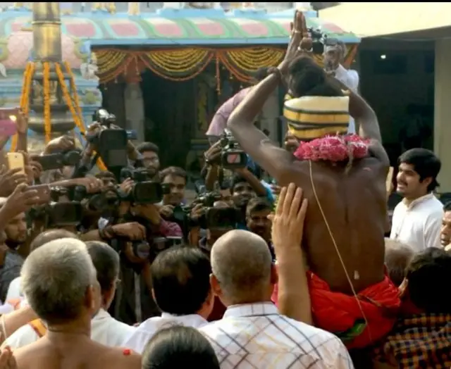 ਪੁਜਾਰੀ, ਸੀਐਸ ਰੰਗਾਰਾਜਨ ਆਦਿਤਿਆ ਨੂੰ ਮੋਢਿਆਂ ਤੇ ਚੁੱਕ ਕੇ ਲਿਜਾਂਦੇ ਹੋਏ, ਪਿੱਛੇ ਤੋਂ ਲਈ ਗਈ ਤਸਵੀਰ