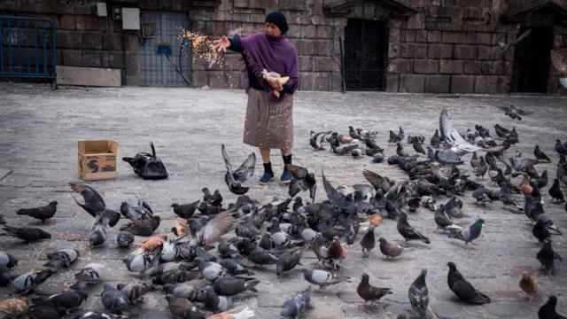 Una señora alimenta a las palomas en la Plaza de San Francisco de Quito, Ecuador.