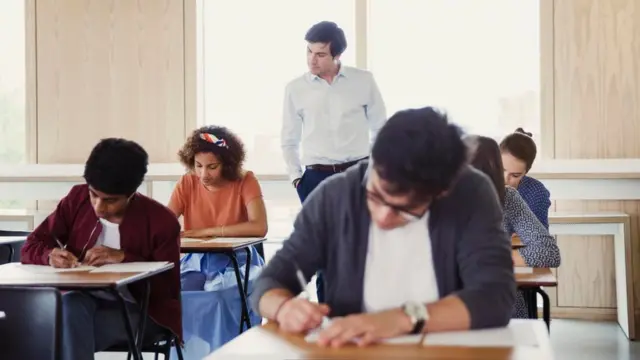 مدرس يتابع أداء طلابه في فصل دراسي