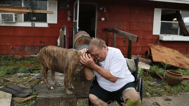 Evi kasırgadan hasar gören bir adam, köpeğine sarılıp ağlarken
