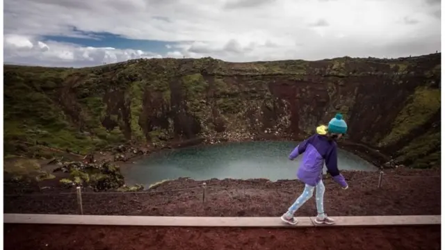 Msichana mdogo akitazama ziwa lililotengezwa na mlipuko wa volakano