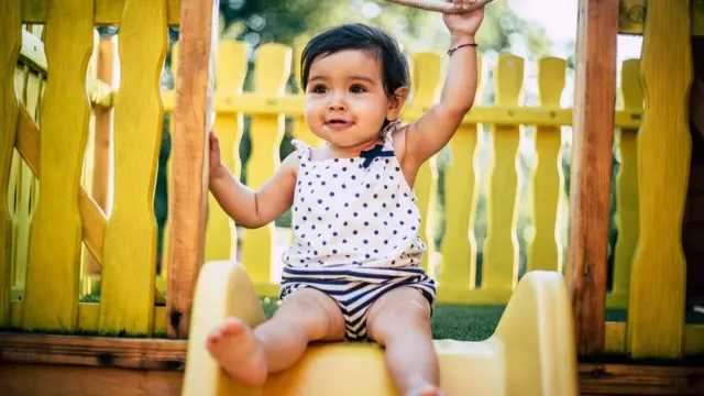 Una bebé jugando en una resbaladera.