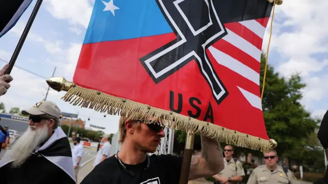 Homem segura bandeira com símbolo nazista e o nome dos EUA