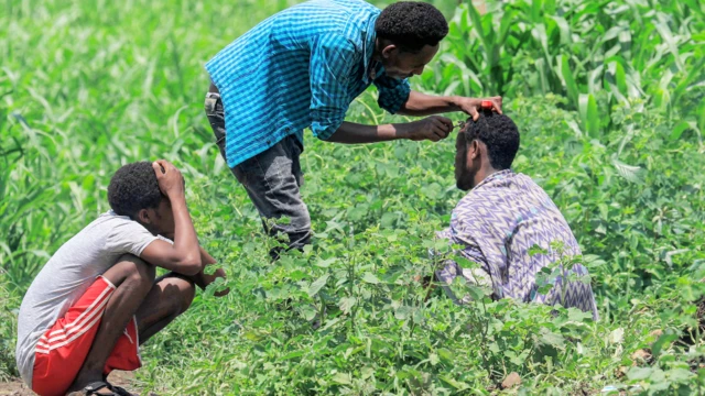 Wani mutum a zaune yayin da wani yake masa aski da reza a sansanin yan gudun hijirar Ethiopia na kabilar Qemant a kauyen Basinga a gundumar Basunda dake yankin gabashin Sudan. Talata Agusta 10, 2021
