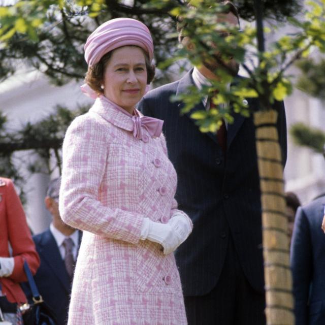 A rainha ao lado de uma muda de carvalho que ela plantou no jardim da casa de hóspedes do governo em Tóquio
