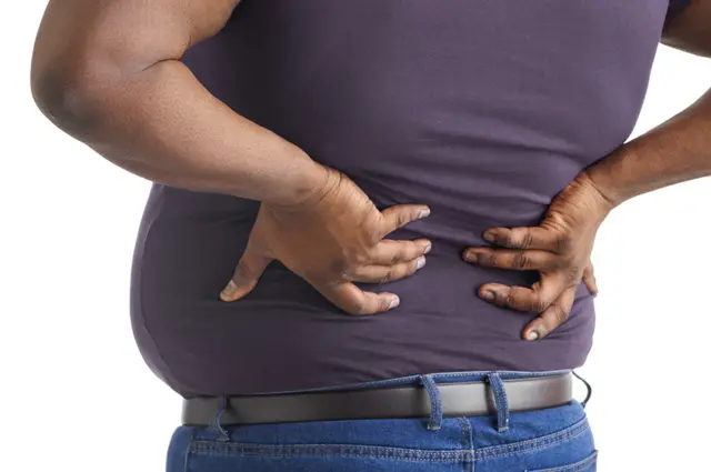 Persona con sobrepeso se agarra la espalda baja