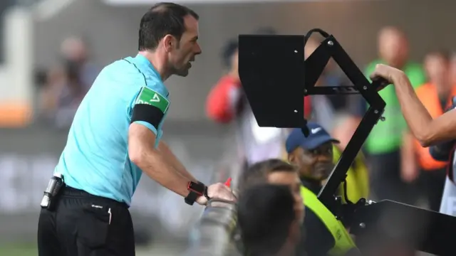 L'arbitre Marco Fritz contrôle l'arbitre assistant vidéo (VAR) lors du match de Bundesliga de première division allemande entre le FC Augsburg et le Borussia Dortmund à Augsburg, dans le sud de l'Allemagne, le 30 septembre 2017
