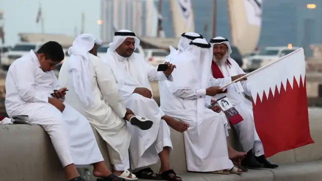 жители дохи держат в руках флаг катара, доха, катар
