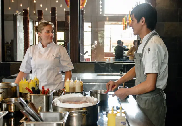 chef habla con un cocinero en medio de una cocina