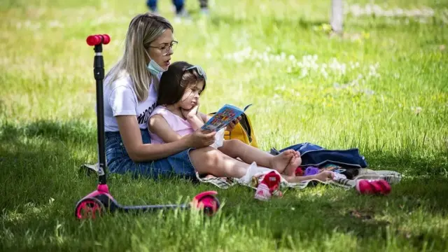 Menina lendo no colo da mãecassino pix betum parque