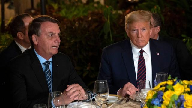 Bolsonaro e Trump jantando lado a lado em uma mesa
