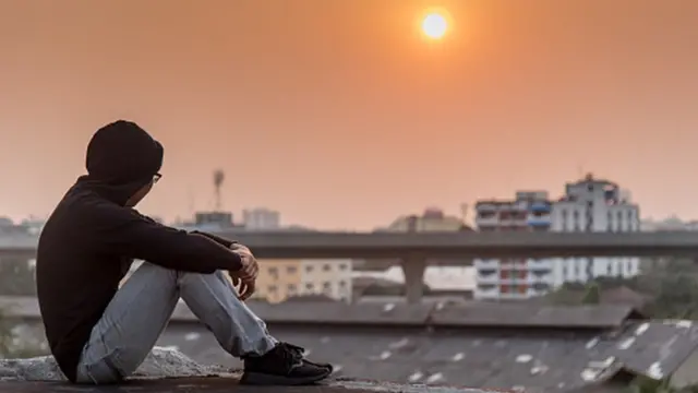 Young male sitting on a rooftop looking out