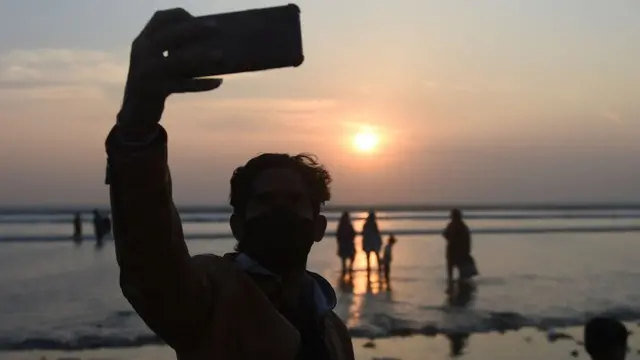 پاکستان کے شہر کراچی کے ساحل پر نوجوان نے سال 2021 کے آخری غروب آفتاب کی سیلفی لی