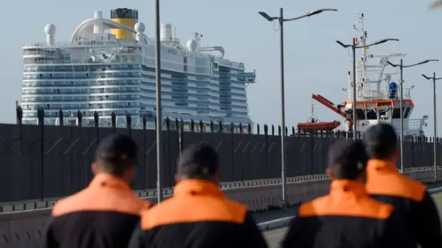 Miembros de la guarda costera italiana marchan frente al Costa Smeralda