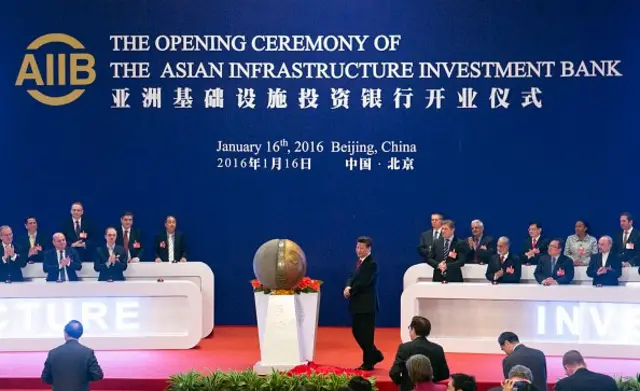 ผู้แทนของชาติที่ร่วมก่อตั้งธนาคารเพื่อการลงทุนในโครงสร้างพื้นฐานเอเชีย (AIIB) ปรบมือให้แก่ประธานาธิบดีสี จิ้นผิง ของจีน (กลาง) ขณะเปิดรูปปั้น ระหว่างพิธีเปิดธนาคารเอไอไอบีในกรุงปักกิ่ง เมื่อวันที่ 16 ม.ค. 2016