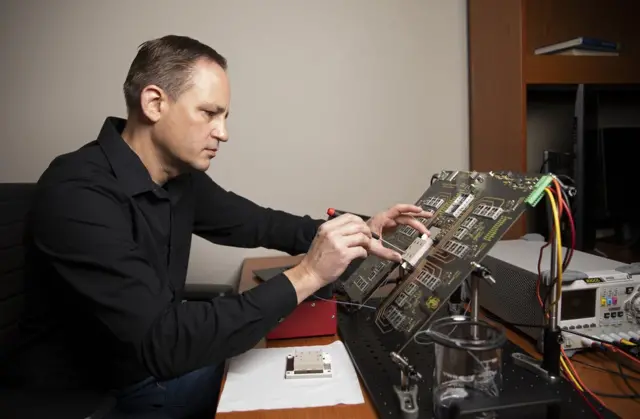 GTRI மூத்த ஆய்வுப் பொறியாளர் கிறிஸ் ஷேப்பர்ட் மைக்ரோ சிப்பை ஆராய்கிறார்.