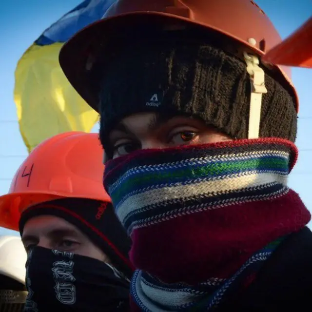 Учасник демонстрації в балаклаві з каскою