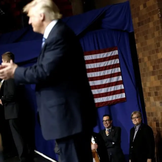 Bannon mirando a Trump desde atrás de un escenario.