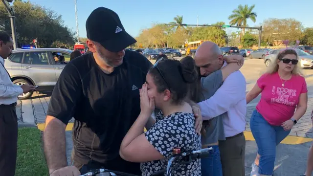 Varias personas se abrazan afuera de la secundaria Stoneman Douglas