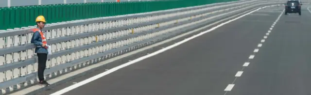 A construction worker stands on a section of the Hong Kong-Zhuhai-Macau Bridge in Zhuhai on March 28, 2018.