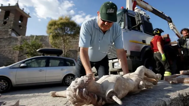 A resident looks at a damaged crucifix after an earthquake in central Italy