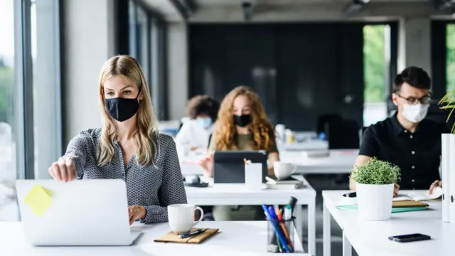 Trabalhadores com suas máscaras trabalhandojogo cassino que ganha dinheiroseus laptops