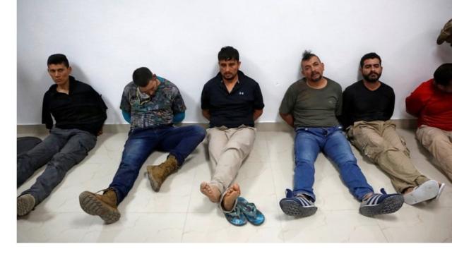 Men accused of the president's assassination sit against a wall