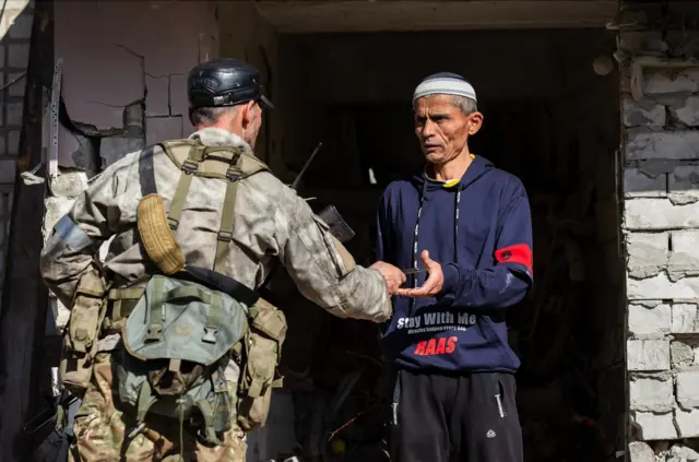 26 апреля, Украина. Луганская область. Рубежное. Боец чеченского добровольческого батальона "Ахмат" проводит проверку документов у местного жителя.