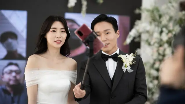 전광판 앞에서 접속한 하객들과 단체사진을 찍고 있는 신랑 신부