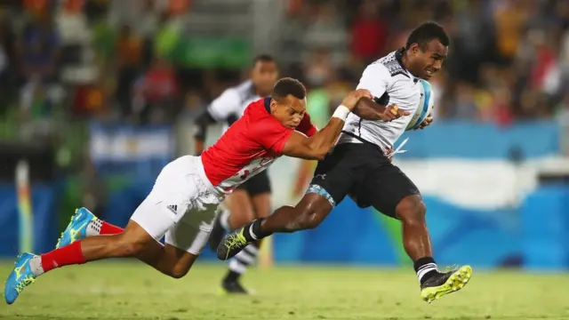 Un jugador británico trata de derribar a un jugador de Fiyi