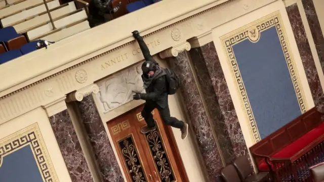 A protester jumps over a balcony to reach the Senate floor