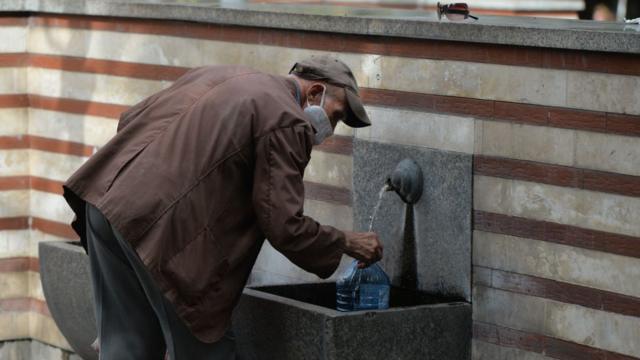 Hombre bebiendo agua de una fuente en Sofía, Bulgaria.