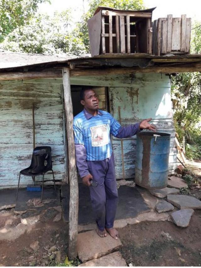 Un hombre frente a una casa miseria