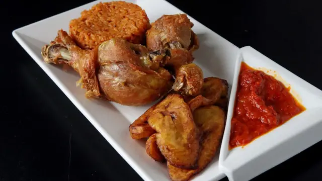 Riz jollof avec poulet et bananes plantains frites au restaurant nigérian Obosa dans le quartier de Roslindale à Boston.