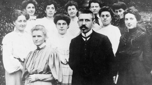 Marie Curie y Paul Langevin adelante con un grupo de mujeres atrás.